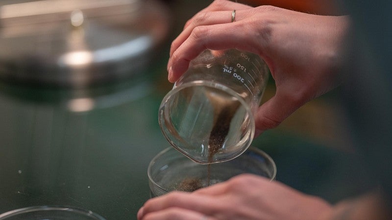 Beaker of volcanic sample being poured into dish