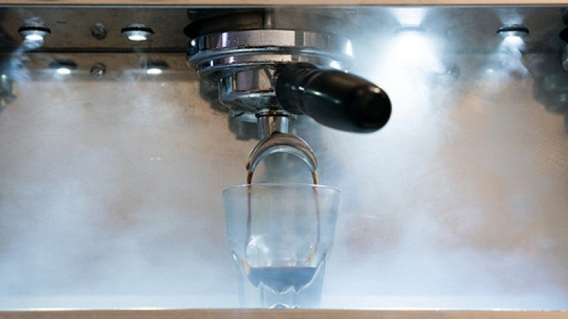 Steam surrounds brewing espresso shot