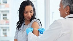 woman with a band-aid on her upper arm after receiving a vaccine from a medical provider