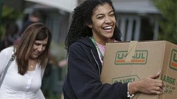 Smiling student moving boxes into residence hall