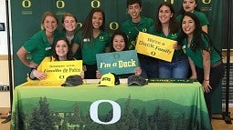 A group of students gather around a table to celebrate enrolling at UO