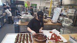 Chefs dipping strawberries in chocolate in the new central kitchen.