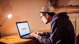 Man with tinfoil hat with laptop