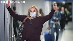 Woman in face mask giving thumbs-up
