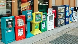 Row of newspaper boxes on sidewalk