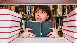 student peering through library stacks