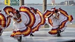 Image shows Mexican folklore dancers moving about in Jalisco