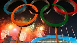 Image shows the Olympic rings in front of a stadium