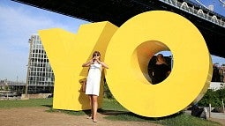 UO student throwing the O in front of the 'YO' statue in New York City