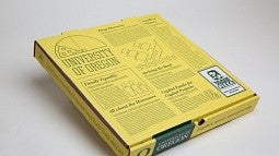 A pizza box featuring news stories about the UO
