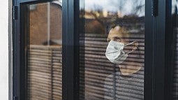 Man wearing mask looking out window