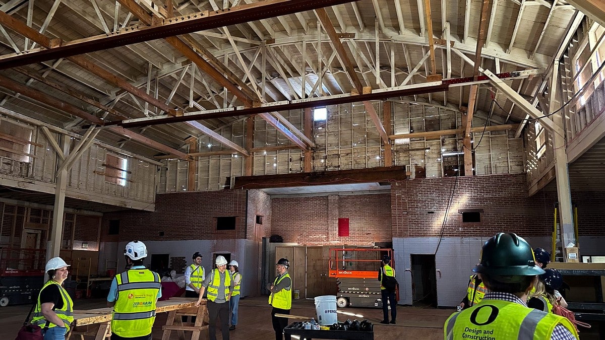 People in hard hats tour inside of Highland Hall