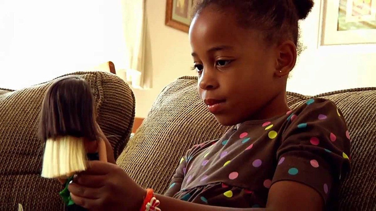 A black girl playing with a doll