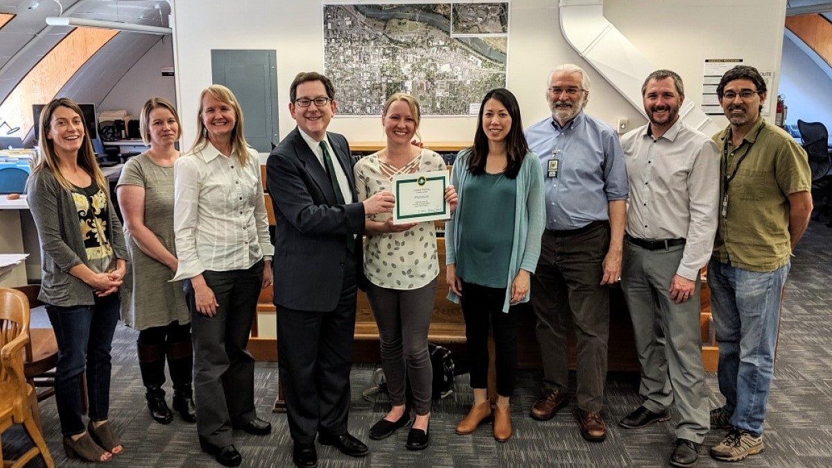 University of Oregon President Michael Schill delivers the Green Office Program’s platinum certification to the Campus Planning Office 