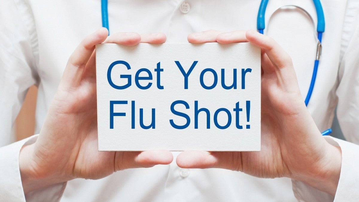 Doctor holding card reading 'Get your flu shot'