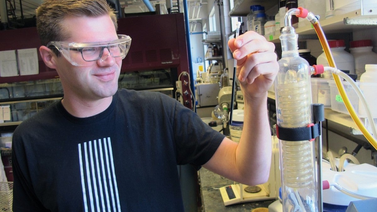 Doctoral student Gabe Rudebusch holds a tube with his molecules in solution