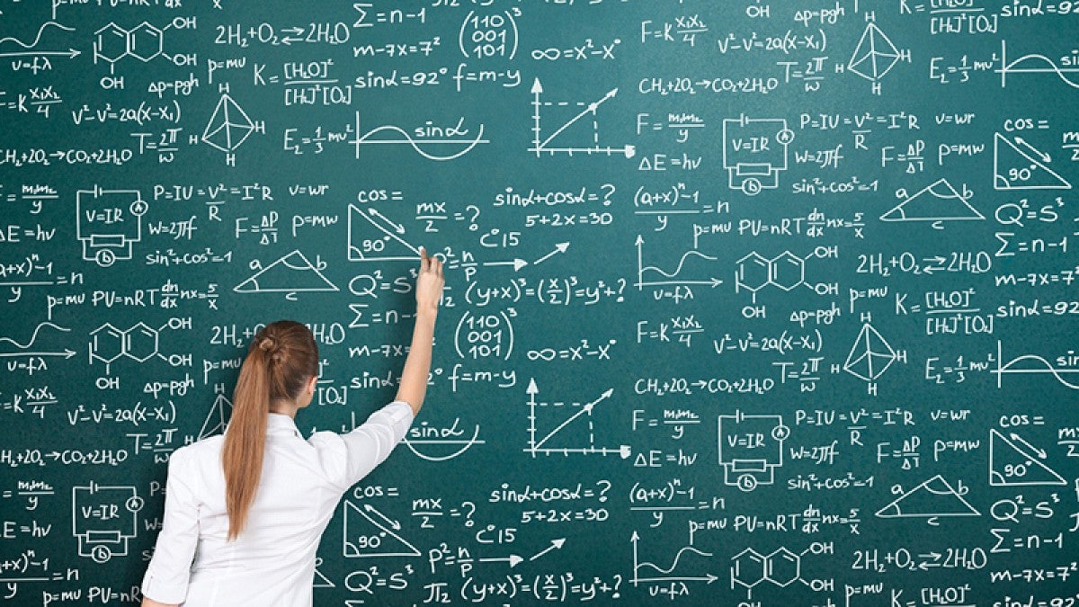 Woman writing math problem on chalkboard