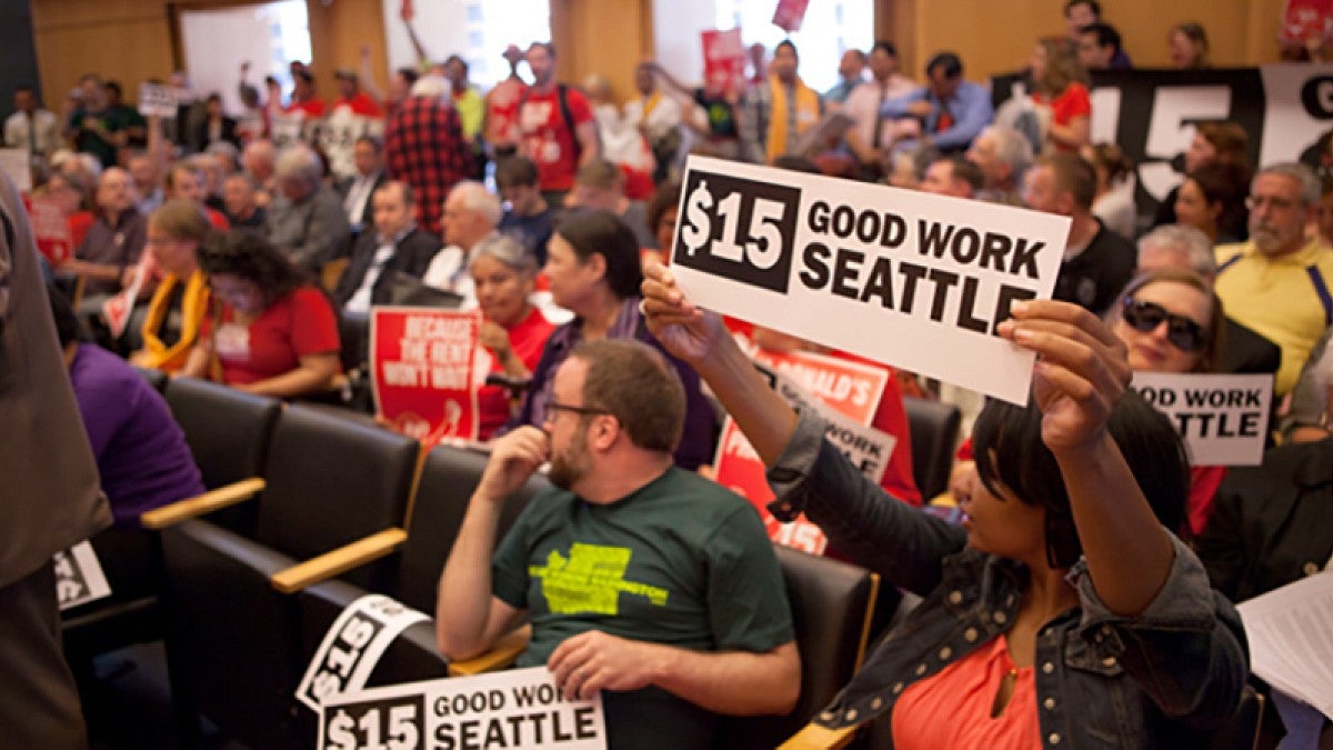 People holding signs at a Seattle meeting on the minimum wage