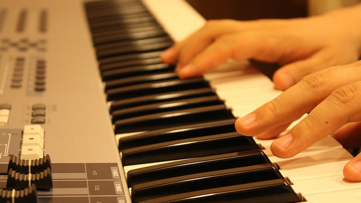 Image shows the hands of a piano player while playing music