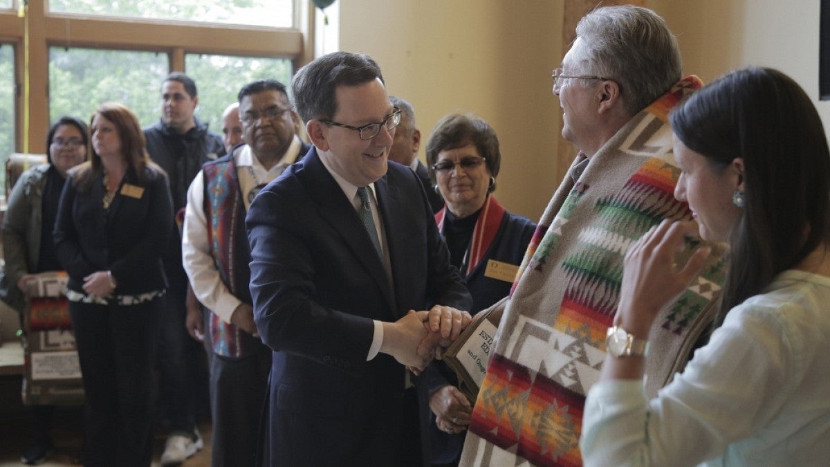 UO President Michael Schill shakes hands with Don Gentry, chairman of the Klamath Tribal Council at the Many Nations Longhouse