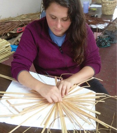Amanda Craig, seen here weaving with cattails, uses native species to provide ecosystem services like bioswale filtering.