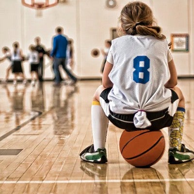 Youth basketball player sitting on ball